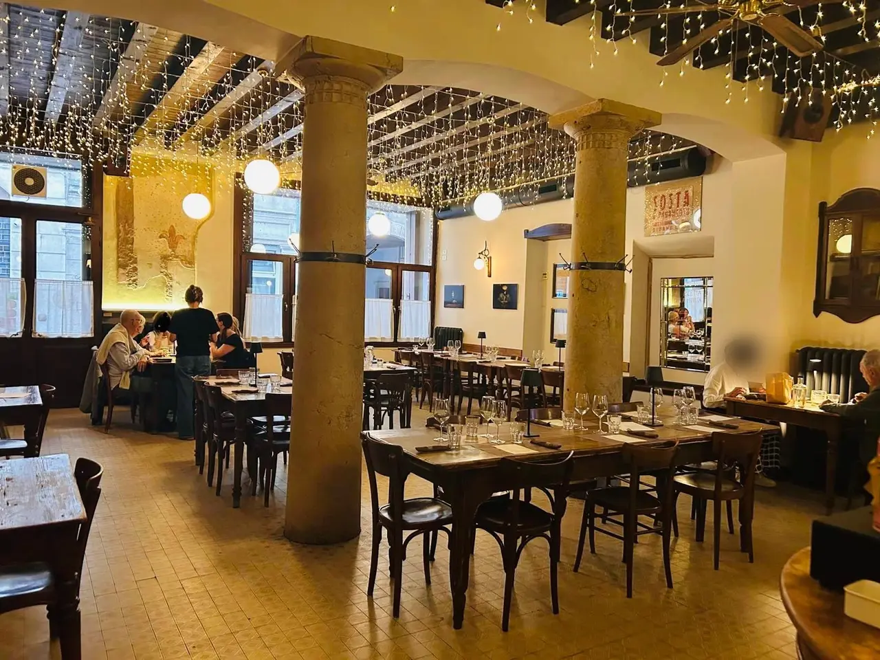 Sala interna dell'Osteria Due Spade con colonne in pietra e luci a stringa